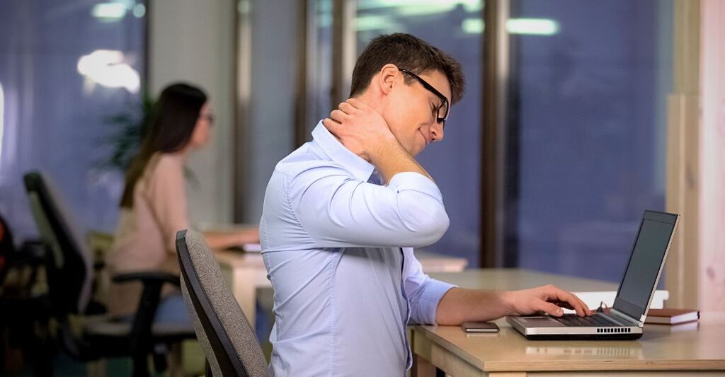 Un uomo e una donna seduti in ufficio con conseguenze fisiche della sedentarietà.