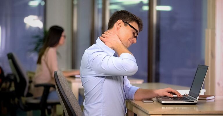 Un uomo e una donna seduti in ufficio con conseguenze fisiche della sedentarietà.