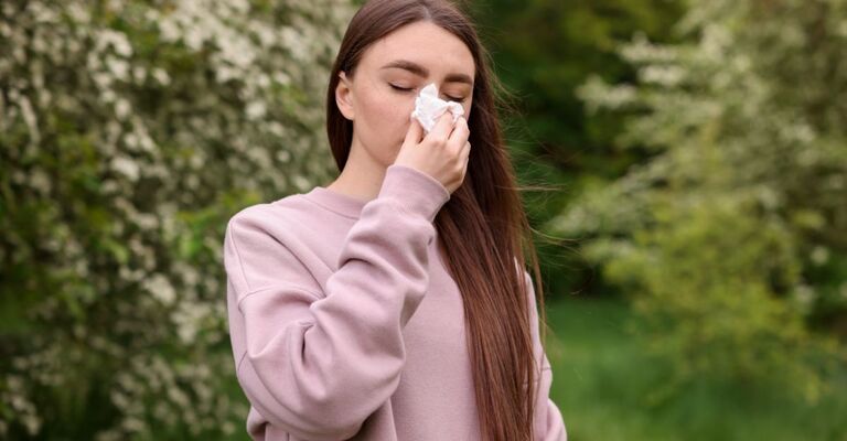 Una ragazza si soffia il naso in mezzo ad un bosco