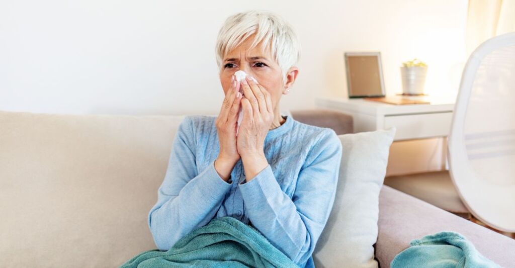 Una donna che si soffia il naso sul divano
