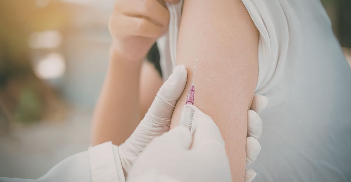 Primo piano di un operatore sanitario con guanti bianchi che somministra un vaccino sul braccio di una persona