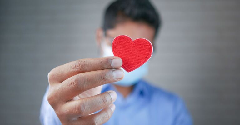medico-che-tiene-tra-le-dita-un-cuore-ritagliato-di-cartoncino