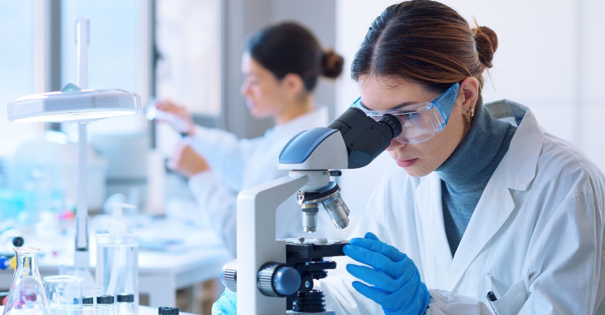 Ricercatori che lavorano nel laboratorio clinico. Primo piano su una ricercatrice al microscopio