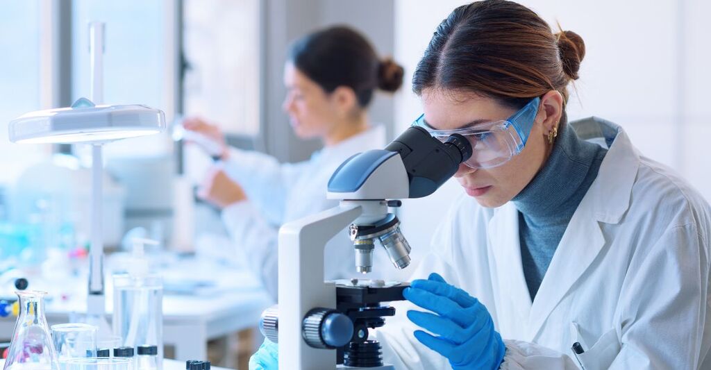 Ricercatori che lavorano nel laboratorio clinico. Primo piano su una ricercatrice al microscopio