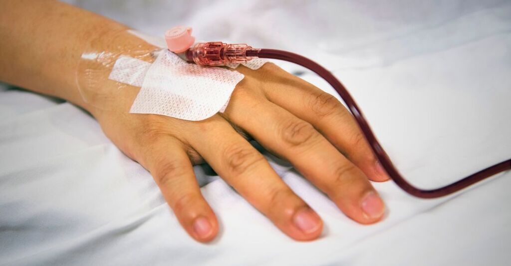 La mano di un uomo mentre fa una trasfusione.