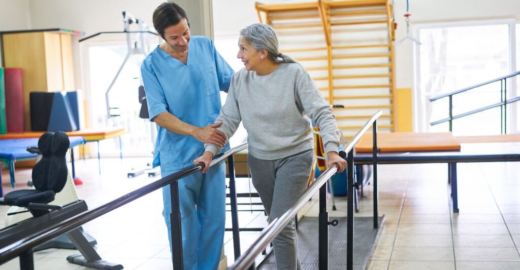 Fisioterapista assiste un'anziana in una seduta di terapia del movimento