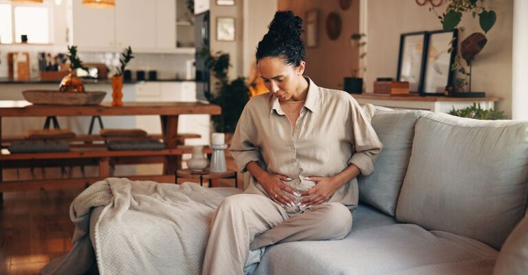 Un giovane medico latino, felice e ottimista, incontra la paziente dopo la visita, le tocca le mani in un gesto di sostegno, le comunica buone notizie dal referto medico, sorridendo.