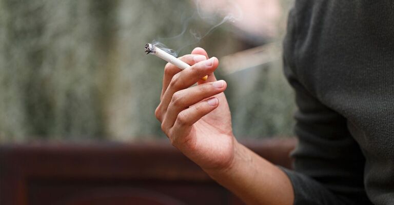 Uomo che tiene in mano una sigaretta fumante