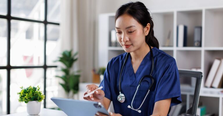 Una dottoressa asiatica attraente e professionale con camice blu, oppure una dottoressa asiatica che lavora ai suoi casi medici alla sua scrivania in un ufficio ospedaliero.