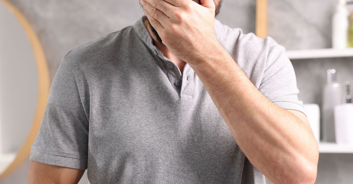 Un uomo con la mano davanti alla bocca dopo un rigurgito acido