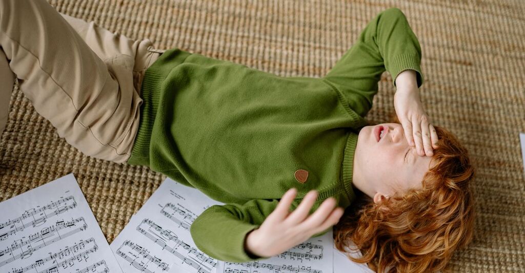 bambino con forte mal di tesa, sdraiato per terra