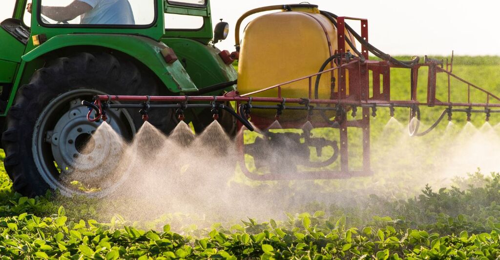 Un trattore che spruzza un pesticida su un campo