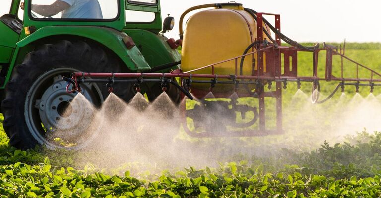 Un trattore che spruzza un pesticida su un campo