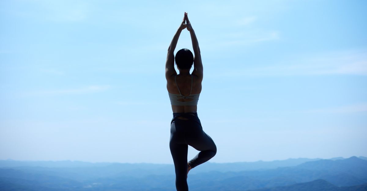 Una persona di spalle in una posizione di yoga all'aperto con vista sulle montagne.