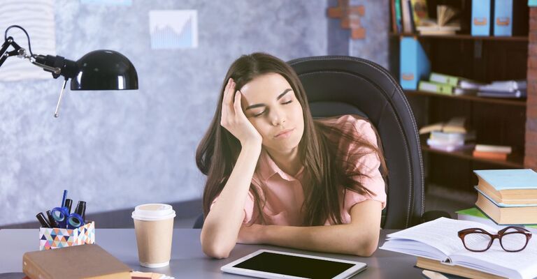 ragazza seduta alla scrivania, assonnata