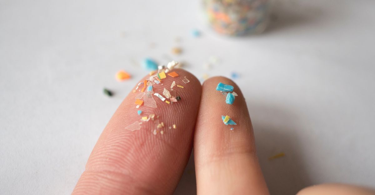 Primo piano di polpastrelli ricoperti da minuscoli frammenti di plastica colorata (microplastiche)