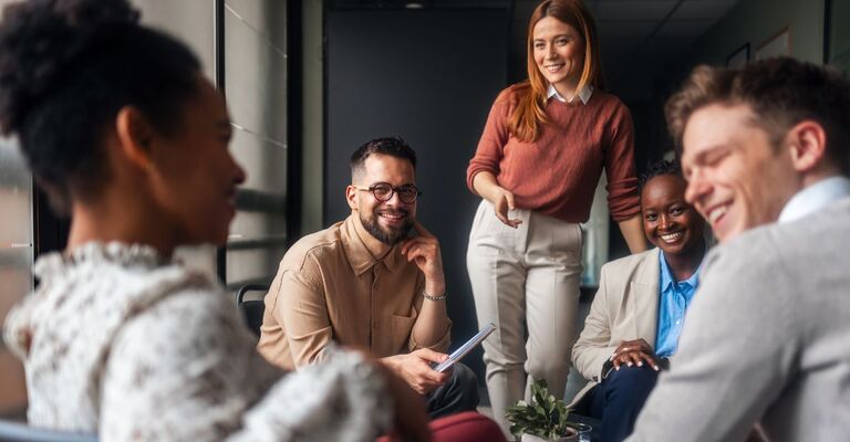 Gruppo di colleghi impegnati in una discussione produttiva in ufficio che sorridono insieme