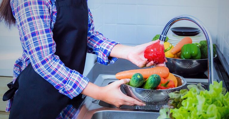 Una donna lava frutta e verdura potenzialmente contaminata.