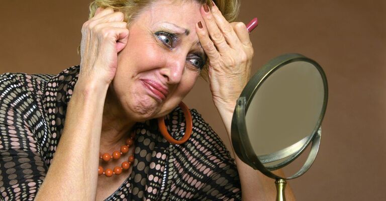Una donna si guarda allo specchio per capire se sta invecchiando più velocemente del suo corpo e si spaventa.