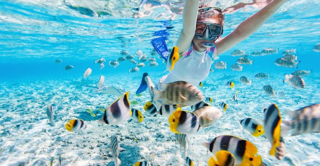 ragazza fa snorkeling con pesci tropicali