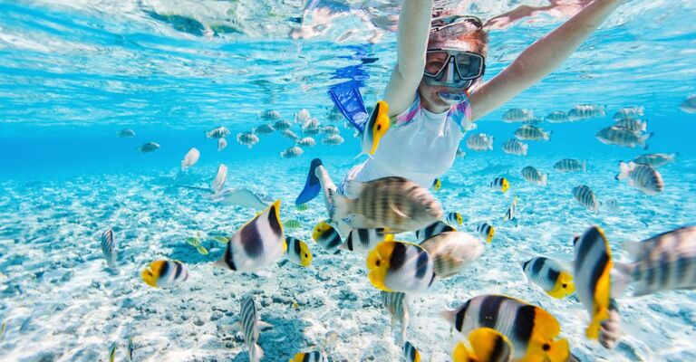 ragazza fa snorkeling con pesci tropicali