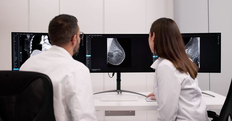 Due ricercatori che guardano le immagini di una mammella al PC