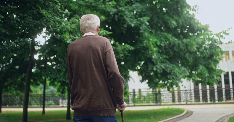 Un anziano che cammina con un bastone