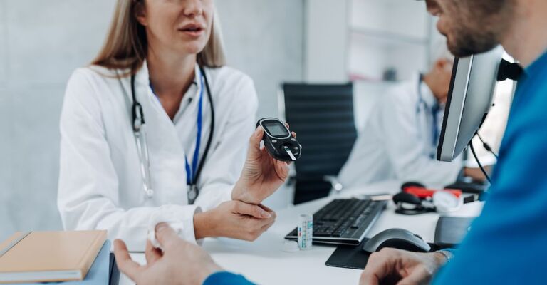 Una dottoressa misura il livello di glicemia di un giovane paziente con un glucometro.
