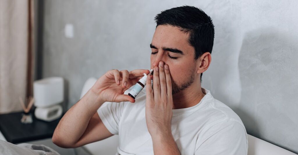 Un uomo mette lo spray nasale.