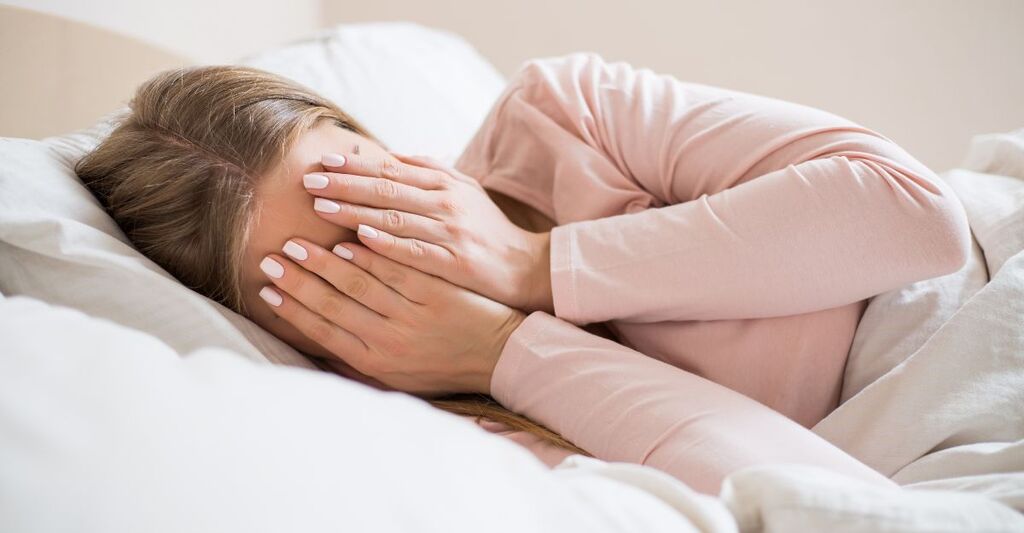 donna nel letto, si copre il volto con le mani