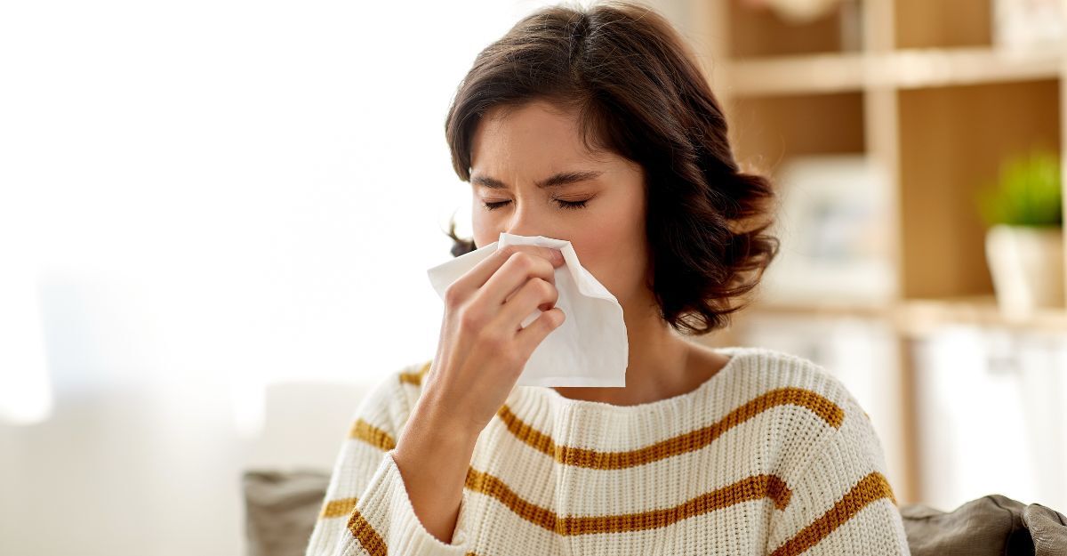 Concetto di assistenza sanitaria, raffreddore, allergia e persone: donna malata che si soffia il naso che cola in un fazzoletto di carta a casa.