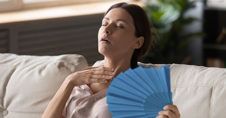 Una donna si sventola con il ventaglio su un divano 