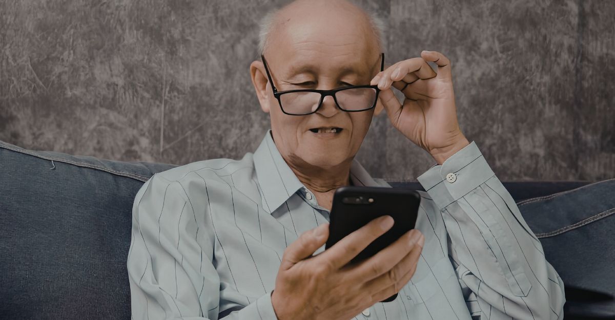 Persona anziana che guarda uno smartphone tenendo in mano un paio di occhiali