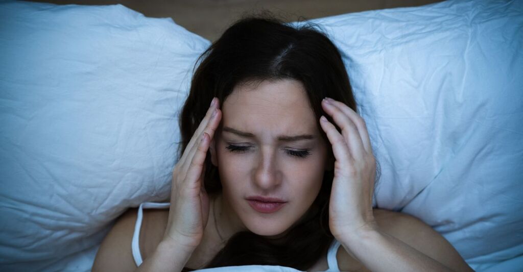 ragazza sdraiata a letto, avverte un forte mal di testa