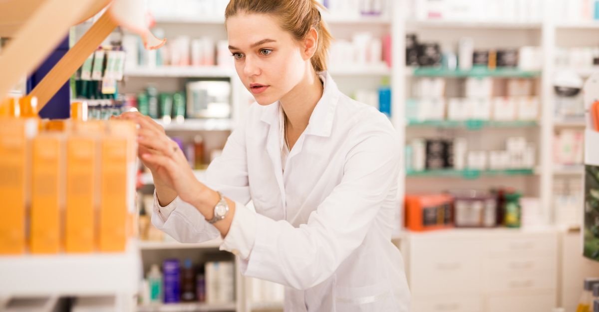 Una farmacista che cerca una medicina tra gli scaffali