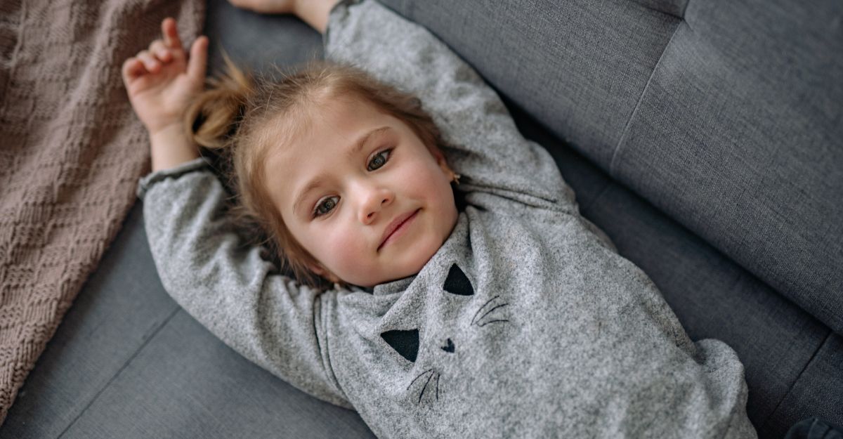 bambina bionda sdraiata a pancia in sù, sul divano