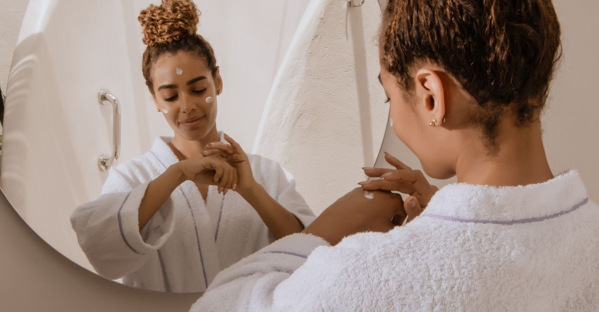 ragazza si applica la crema sul viso, davanti allo specchio