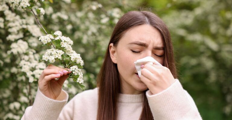 Una ragazza con allergia che si pulisce il naso con un fazzoletto