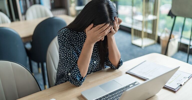 donna al pc, stanca, si tiene il volto con le mani