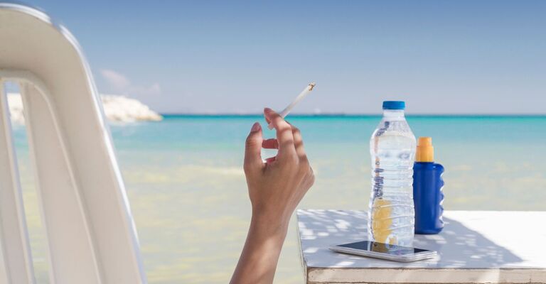 donna fuma sigaretta in spiaggia