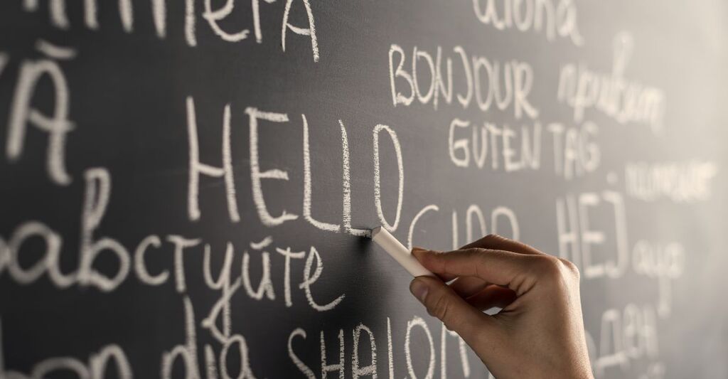 persona-che-scrive-sulla-lavagna-in-diverse-lingue