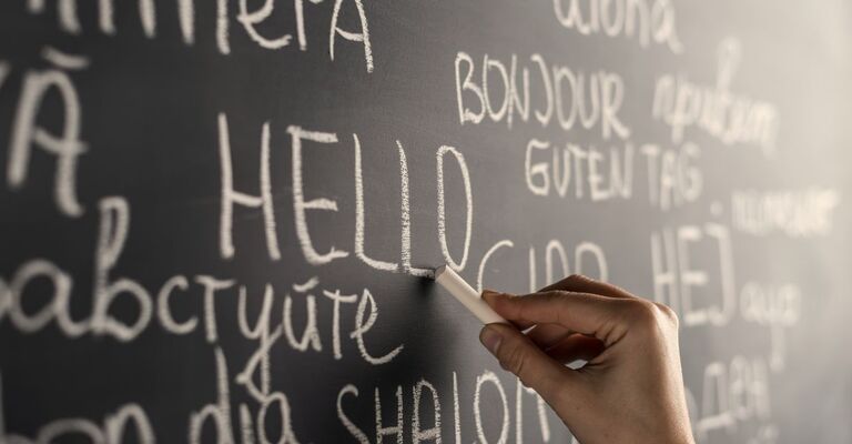 persona-che-scrive-sulla-lavagna-in-diverse-lingue