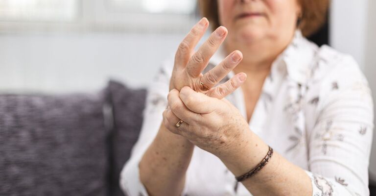 donna affetta da artrite reumatoide si tocca le mani
