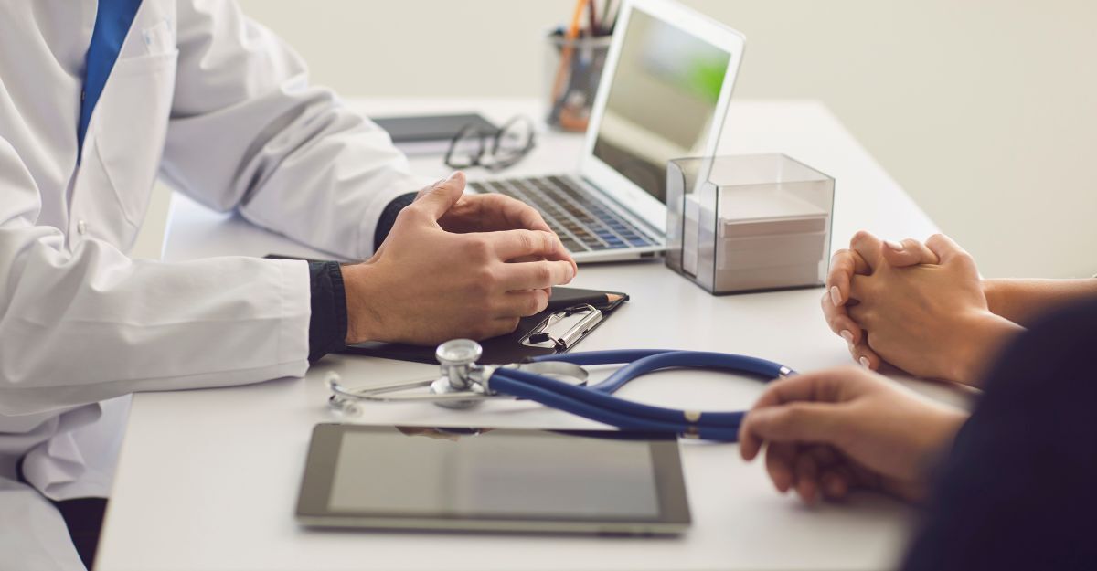 Primo piano delle mani di un medico che parla con dei pazienti