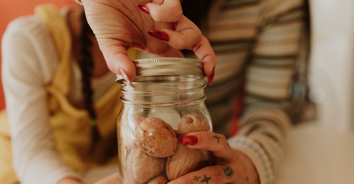mano di donna apre un barattolo contenente delle noci