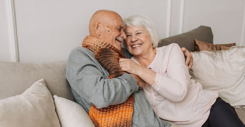 Due anziani sorridenti che si abbracciano