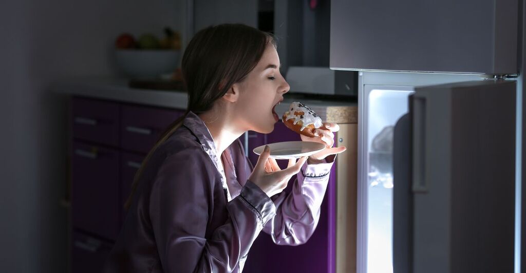 Una ragazza che mangia una ciambella di notte
