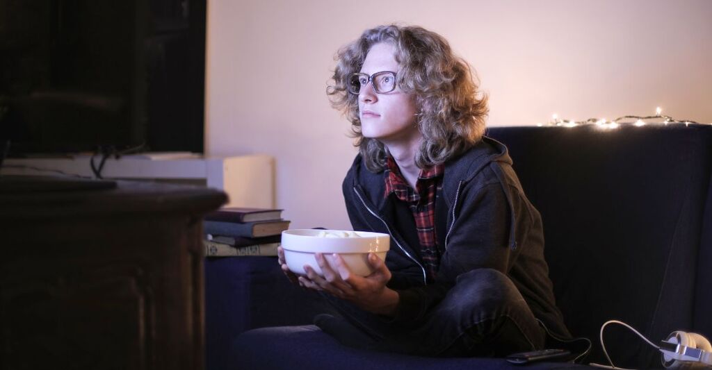 Un ragazzo che guarda la televisione di notte con dei pop corn