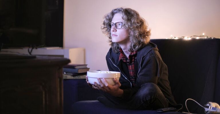 Un ragazzo che guarda la televisione di notte con dei pop corn