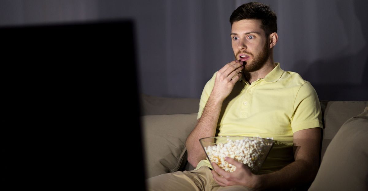 Un ragazzo che guarda la televisione di notte con dei pop corn